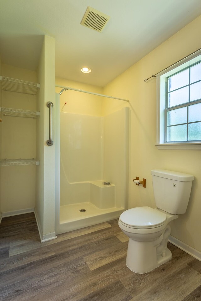 bathroom with walk in shower, toilet, and wood-type flooring