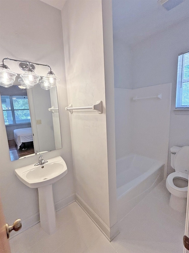 bathroom with tile patterned floors, sink, toilet, and a tub to relax in