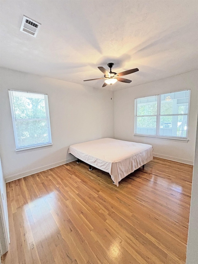 unfurnished bedroom with ceiling fan and wood-type flooring