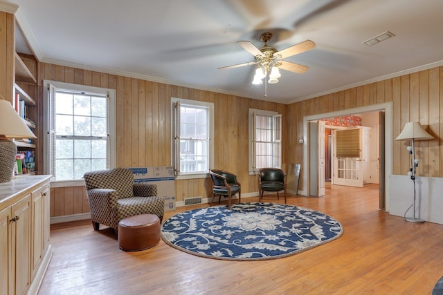 sitting room with light hardwood / wood-style floors, ceiling fan, and crown molding