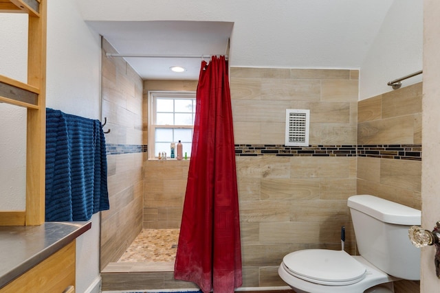 bathroom with a shower with curtain, vanity, toilet, and tile walls