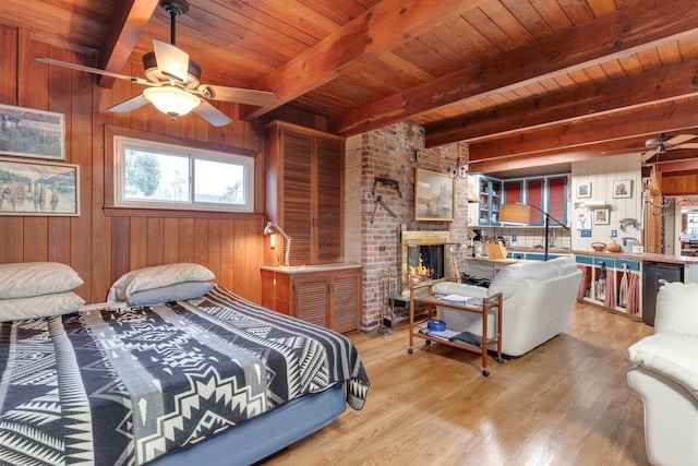 bedroom with beam ceiling, wooden ceiling, wooden walls, and a brick fireplace