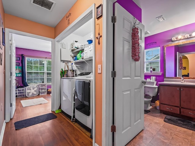 laundry area with washing machine and clothes dryer, sink, and light wood-type flooring