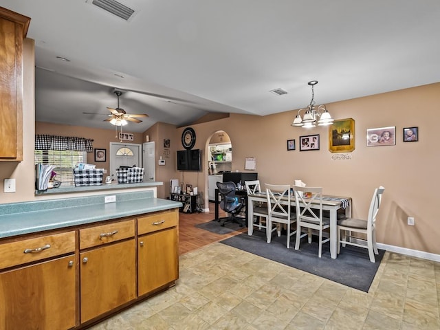 kitchen featuring vaulted ceiling, pendant lighting, and ceiling fan with notable chandelier