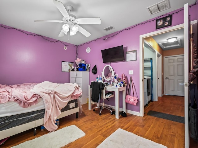 bedroom with washer / clothes dryer, ceiling fan, and hardwood / wood-style flooring