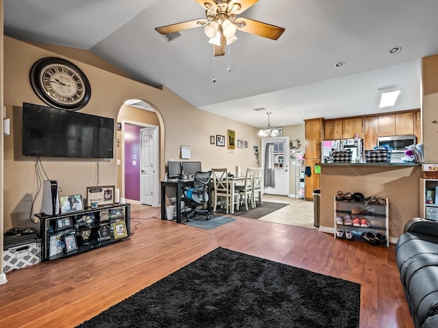 living room featuring wood-type flooring, ceiling fan with notable chandelier, and vaulted ceiling