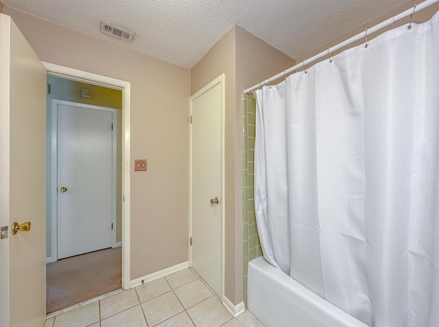 full bathroom featuring a textured ceiling, tile patterned flooring, visible vents, baseboards, and shower / tub combo with curtain