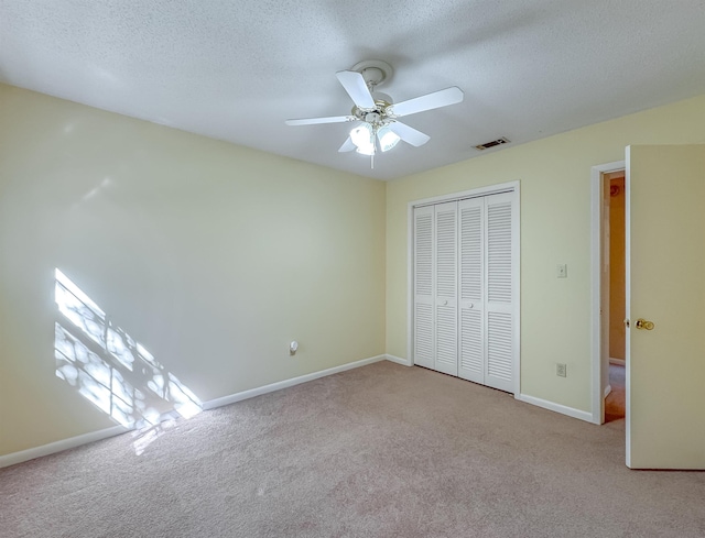 unfurnished bedroom with carpet floors, a textured ceiling, visible vents, and a closet