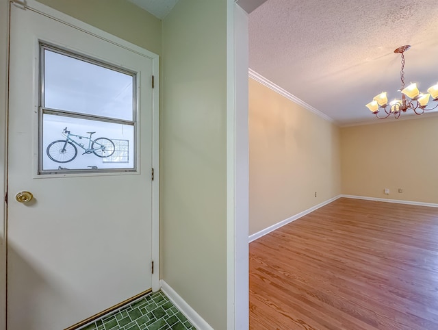 doorway with baseboards, ornamental molding, wood finished floors, an inviting chandelier, and a textured ceiling