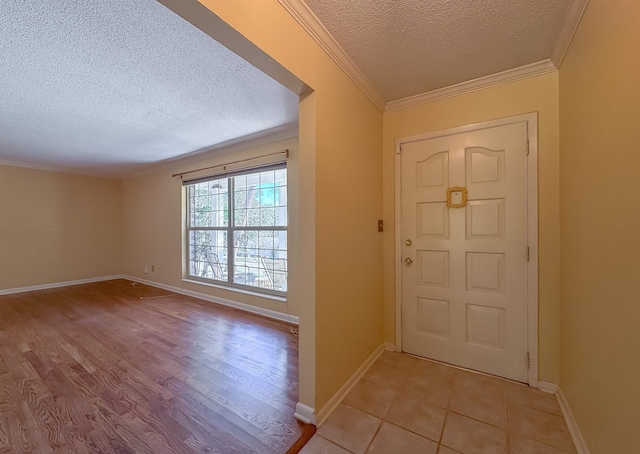 foyer entrance with crown molding, a textured ceiling, baseboards, and light wood finished floors