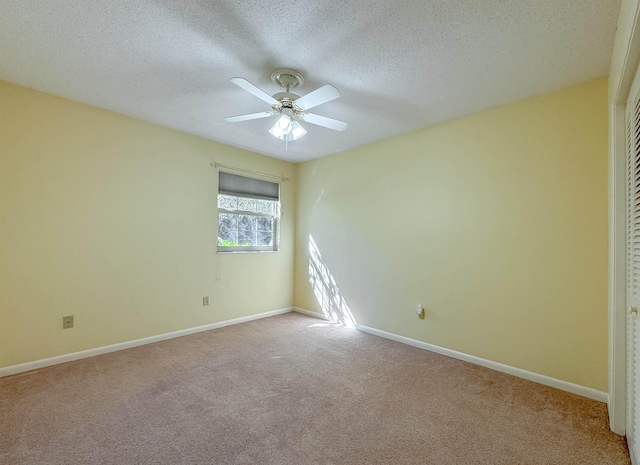 carpeted spare room featuring a ceiling fan, a textured ceiling, and baseboards