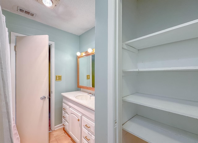 bathroom with tile patterned flooring, visible vents, vanity, and a textured ceiling