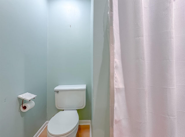 bathroom featuring curtained shower, baseboards, and toilet