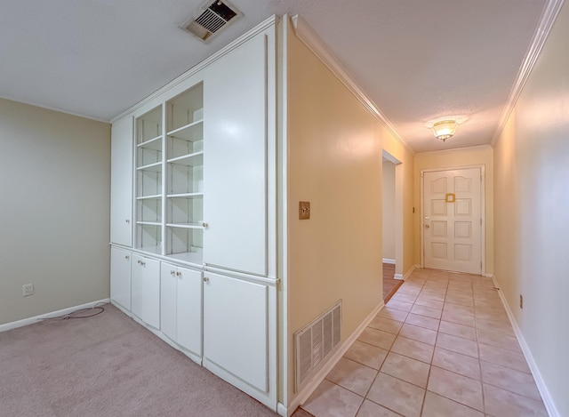 hallway featuring light tile patterned floors, baseboards, visible vents, and ornamental molding