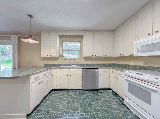 kitchen with a peninsula, white appliances, white cabinetry, and a sink