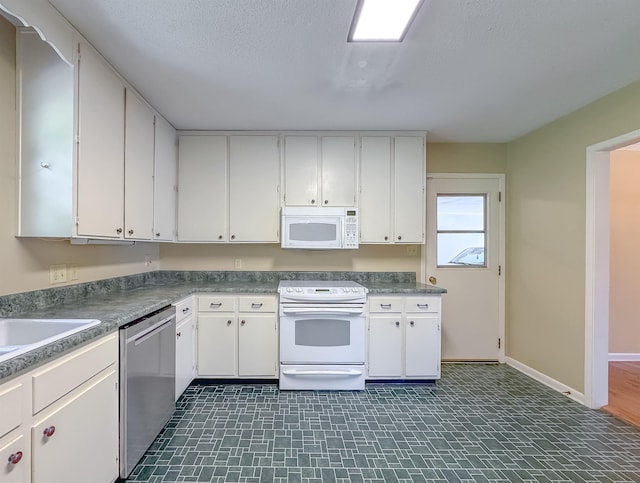 kitchen with a textured ceiling, white appliances, baseboards, white cabinets, and dark countertops