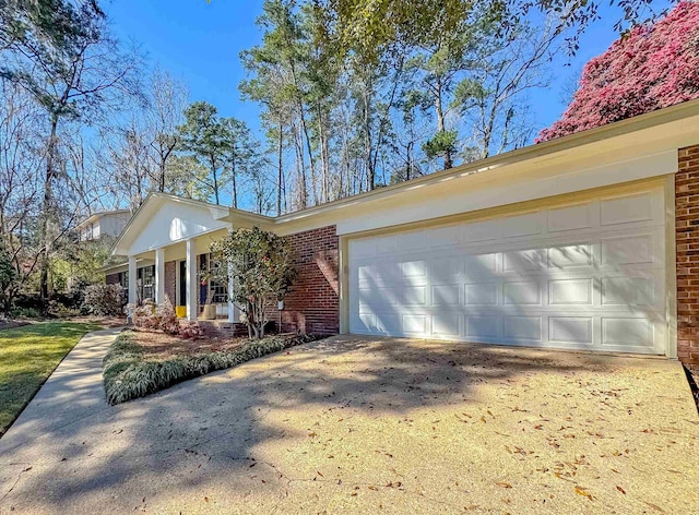 view of front facade with an attached garage, driveway, brick siding, and a porch