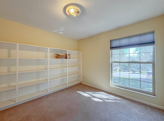 spare room featuring carpet, a textured ceiling, and baseboards