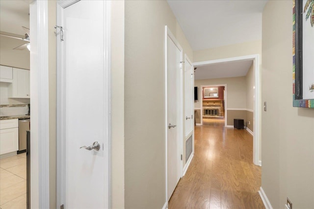 hall with light wood-style flooring and baseboards