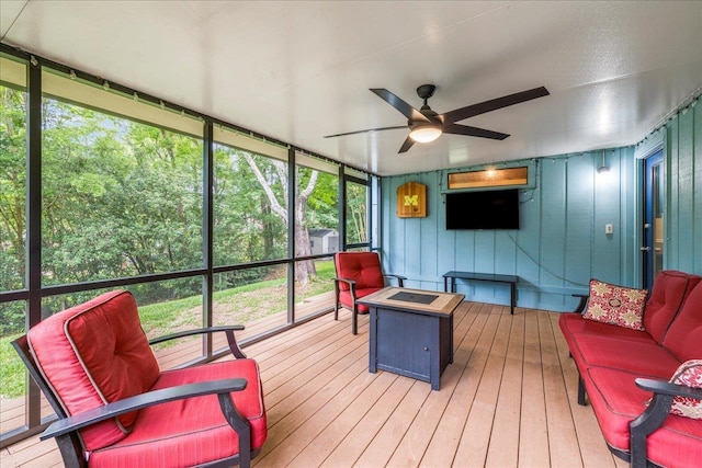 sunroom / solarium with ceiling fan, healthy amount of natural light, and an outdoor living space with a fire pit