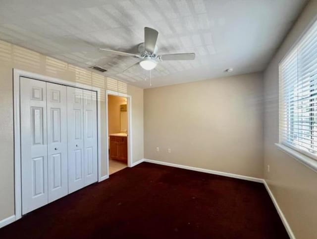 unfurnished bedroom with a closet, ceiling fan, and connected bathroom