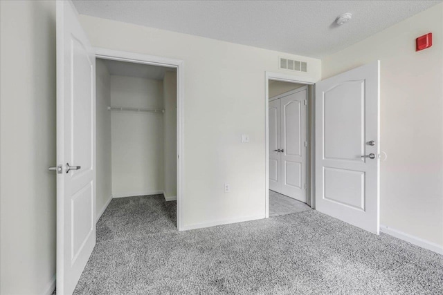 3000 S Adams St Unit 113, Tallahassee, FL 32301 - unfurnished bedroom featuring carpet flooring, a closet, baseboards, a spacious closet, and a textured ceiling