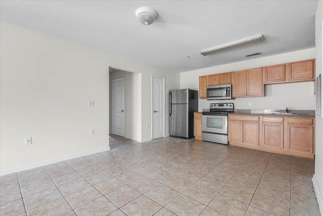 3000 S Adams St Unit 113, Tallahassee, FL 32301 - kitchen with appliances with stainless steel finishes, light tile patterned flooring, a textured ceiling, a sink, and brown cabinetry