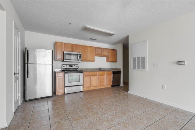 3000 S Adams St Unit 113, Tallahassee, FL 32301 - kitchen with appliances with stainless steel finishes, light tile patterned flooring, a textured ceiling, and baseboards