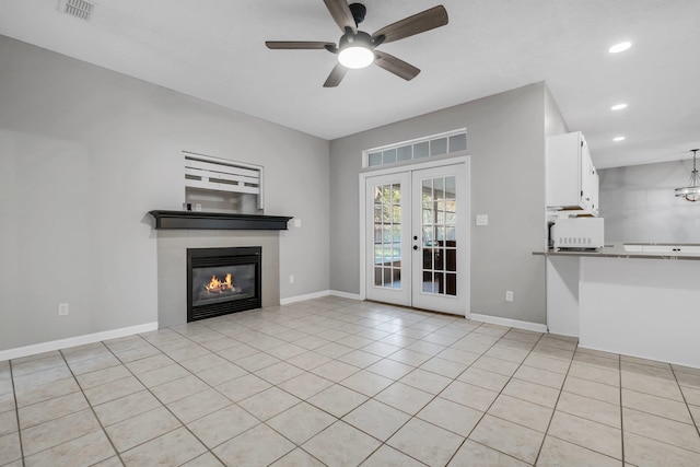 unfurnished living room with a tile fireplace, light tile patterned floors, ceiling fan, and french doors