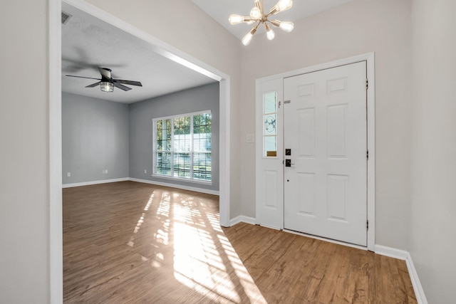 foyer entrance with ceiling fan with notable chandelier and hardwood / wood-style floors