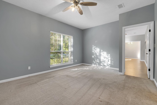 carpeted spare room featuring ceiling fan and a textured ceiling