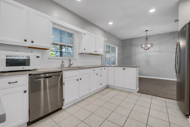 kitchen featuring appliances with stainless steel finishes, decorative light fixtures, tasteful backsplash, white cabinetry, and sink