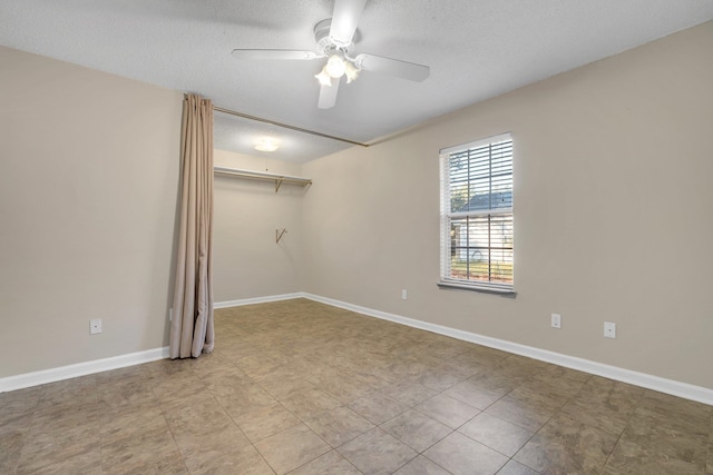 unfurnished room with ceiling fan and a textured ceiling