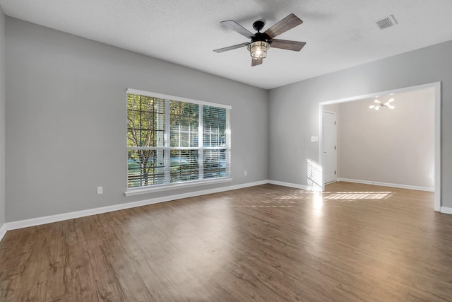 spare room with ceiling fan with notable chandelier, hardwood / wood-style floors, and a textured ceiling