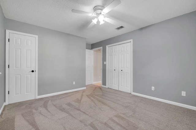 unfurnished bedroom with a closet, light carpet, and a textured ceiling