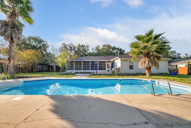 view of swimming pool with a sunroom and a lawn