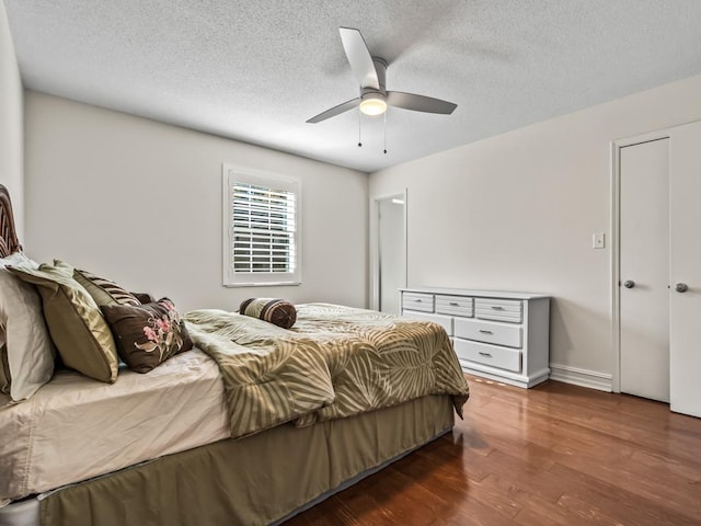 bedroom featuring ceiling fan, a textured ceiling, and dark hardwood / wood-style flooring