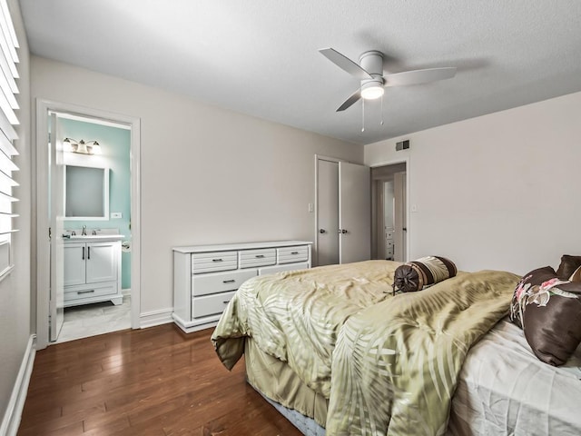 bedroom with ensuite bathroom, ceiling fan, dark wood-type flooring, and sink