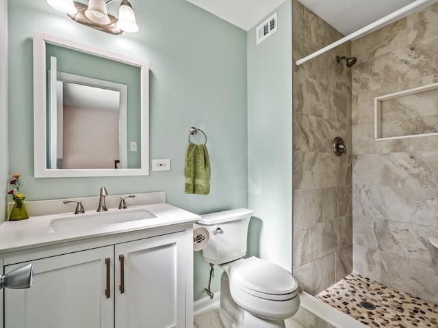 bathroom with tiled shower, vanity, and toilet