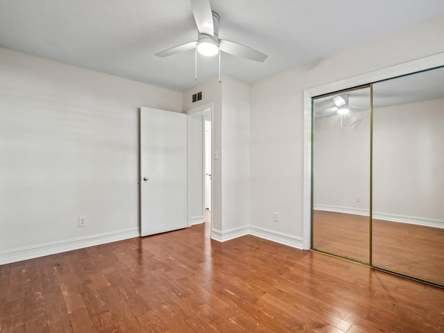 unfurnished bedroom featuring ceiling fan, a closet, and hardwood / wood-style flooring