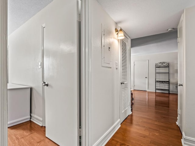 hall with a textured ceiling and light hardwood / wood-style flooring