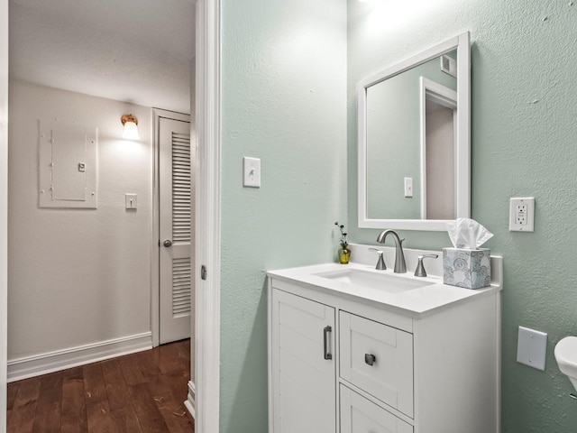 bathroom featuring hardwood / wood-style floors, electric panel, and vanity