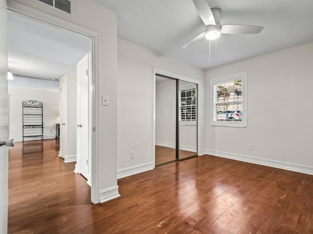 unfurnished bedroom featuring ceiling fan, a closet, and wood-type flooring