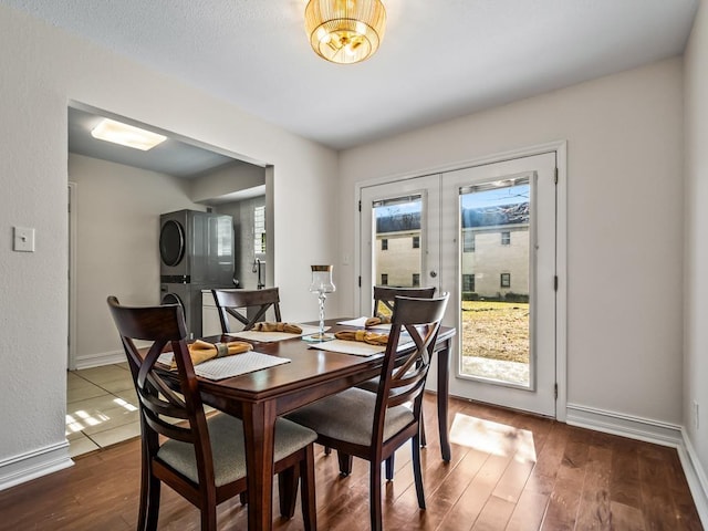 dining room featuring stacked washer and dryer, plenty of natural light, french doors, and dark hardwood / wood-style flooring