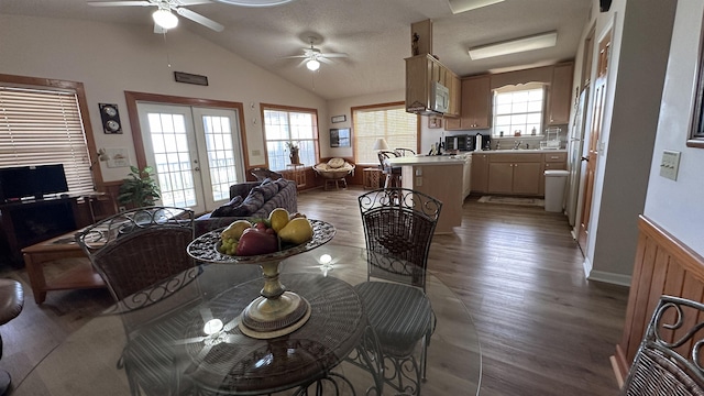 dining room featuring lofted ceiling, wood-type flooring, french doors, and ceiling fan