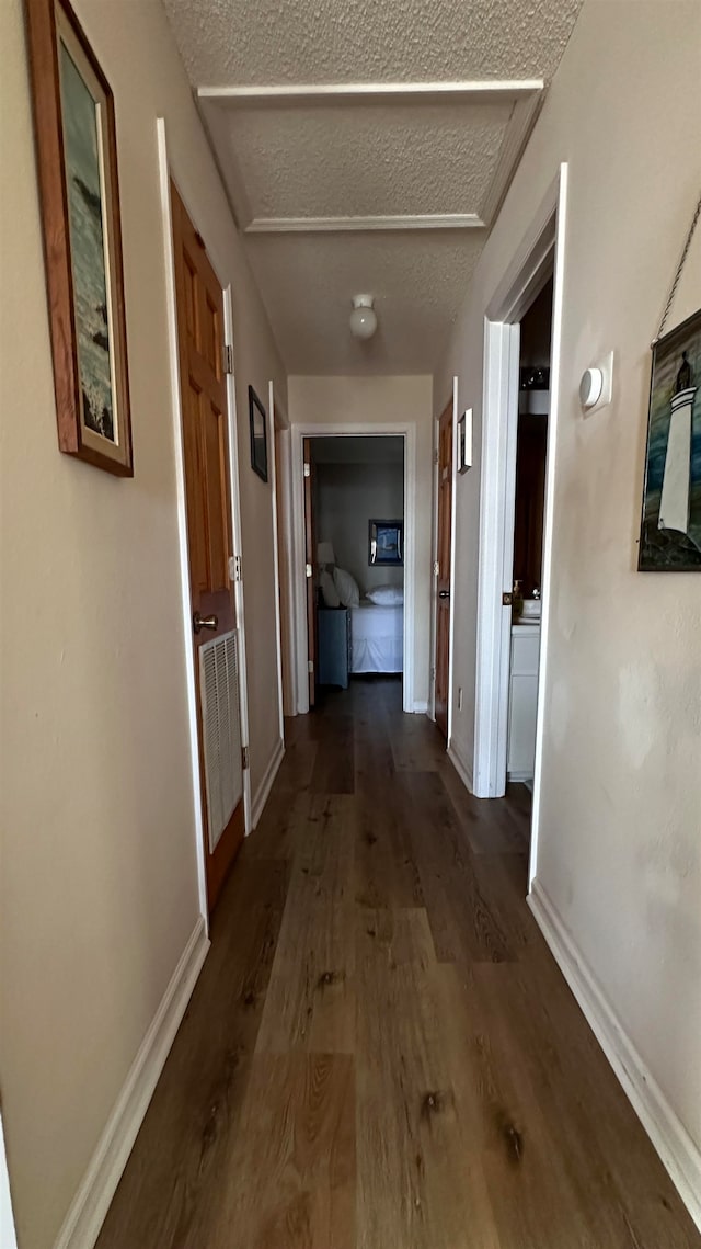 hallway with dark hardwood / wood-style floors and a textured ceiling