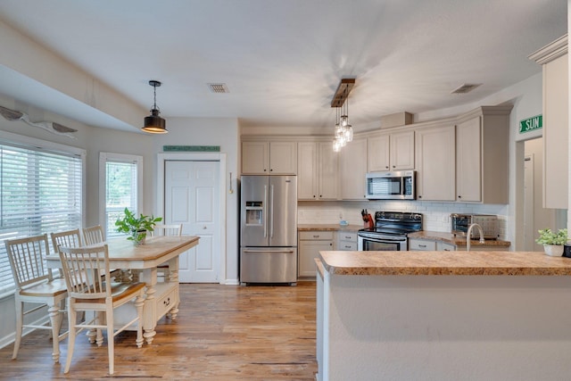 3524 Rosemont Ridge Rd, Tallahassee, FL 32312 - kitchen with appliances with stainless steel finishes, tasteful backsplash, light countertops, light wood-type flooring, and hanging light fixtures