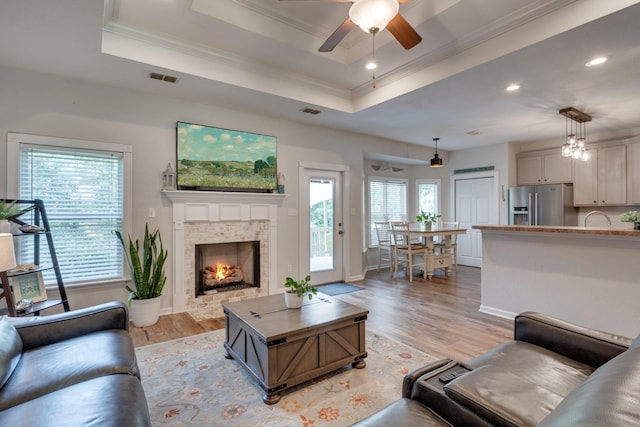 3524 Rosemont Ridge Rd, Tallahassee, FL 32312 - living area featuring crown molding, ceiling fan, a tray ceiling, light wood-style flooring, and a warm lit fireplace