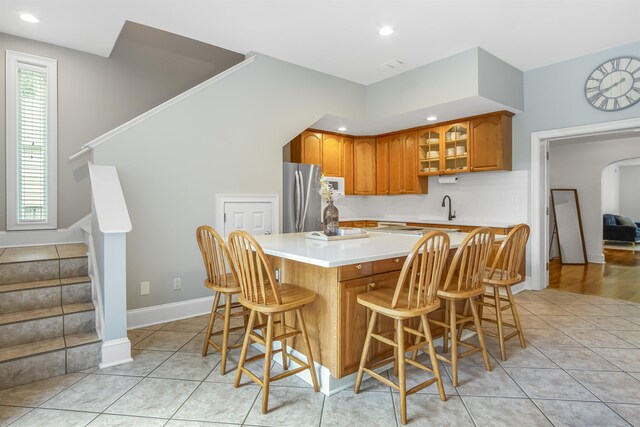 1324 Branch St, Tallahassee, FL 32303 - kitchen featuring freestanding refrigerator, brown cabinetry, light countertops, glass insert cabinets, and white microwave