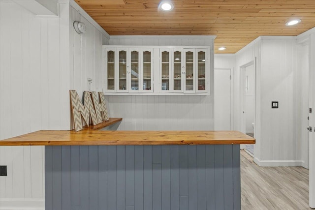 bar featuring white cabinets, light wood-type flooring, wooden walls, and wooden ceiling